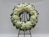 Luxury funeral wreath of roses, orchids and hydrangeas in white and cream tones on a tall stand