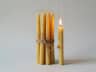 Set of natural beeswax candles tied with twine, one lit candle alongside