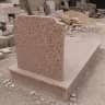 Monument funerar din mozaic cu granulație roz, cu stelă simplă, placă și borduri, în curtea unui atelier de piatră