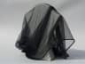 Fine black mourning veil draped over a neutral stand, delicate texture in soft diffused light