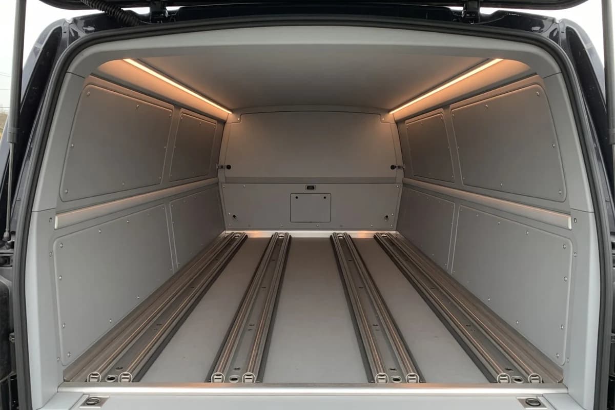 Interiorul unui dric profesionist: șine inox, tapițerie gri impecabilă, lumină caldă discretă