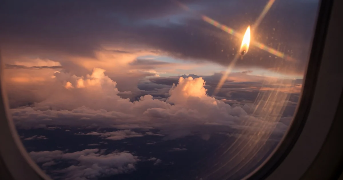 View through airplane window of clouds at golden hour