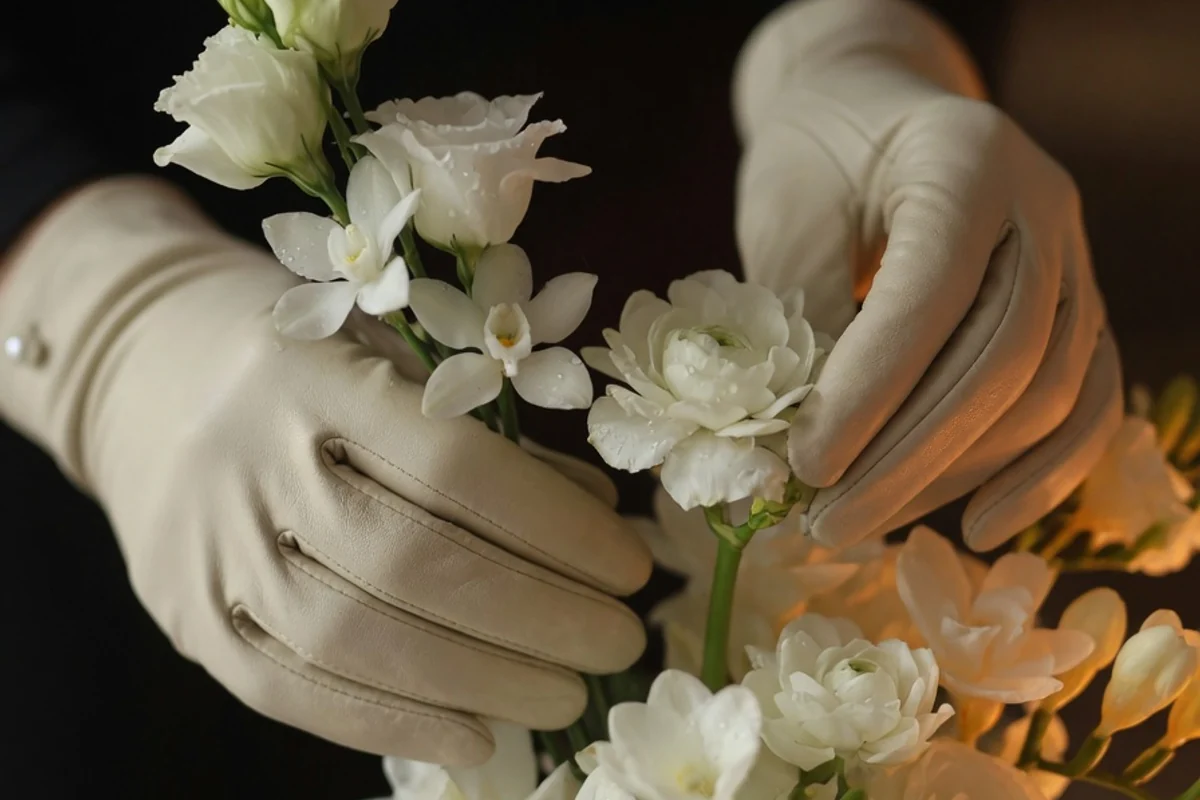 Gloved hands arranging white flowers with care, discreet close-up